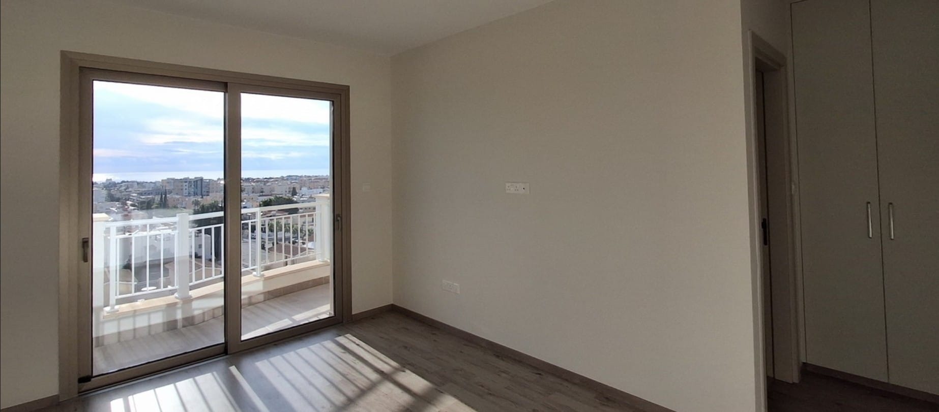 Bedroom with sliding glass doors to a balcony and fitted wardrobe in an apartment in Universal, Paphos