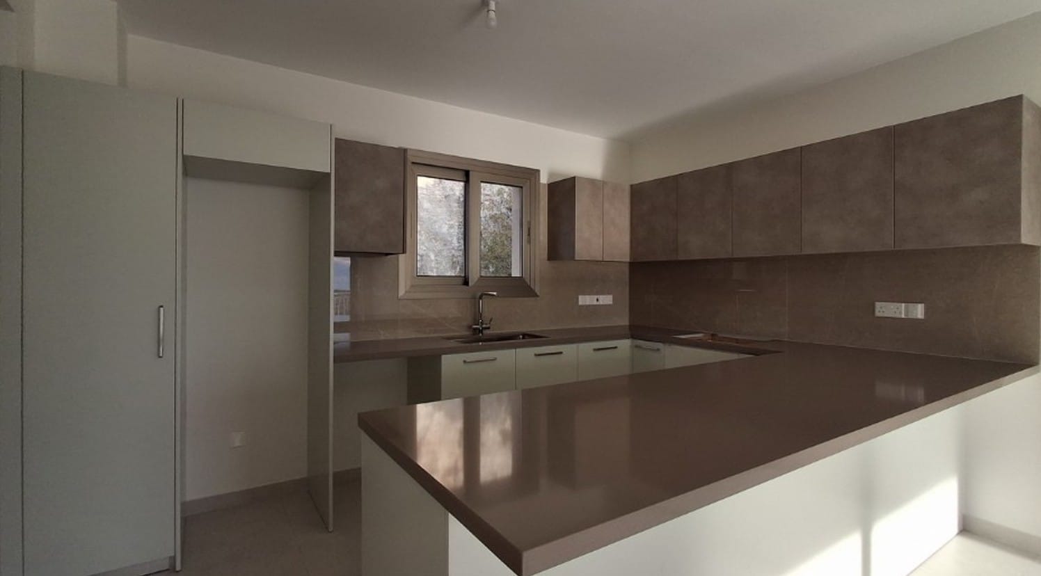 Fitted kitchen with wall and base cabinets and a breakfast counter in an apartment in Universal, Paphos