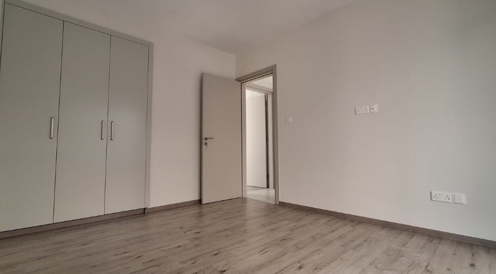 Bedroom with fitted wardrobes and wood-effect flooring in an apartment in Universal, Paphos