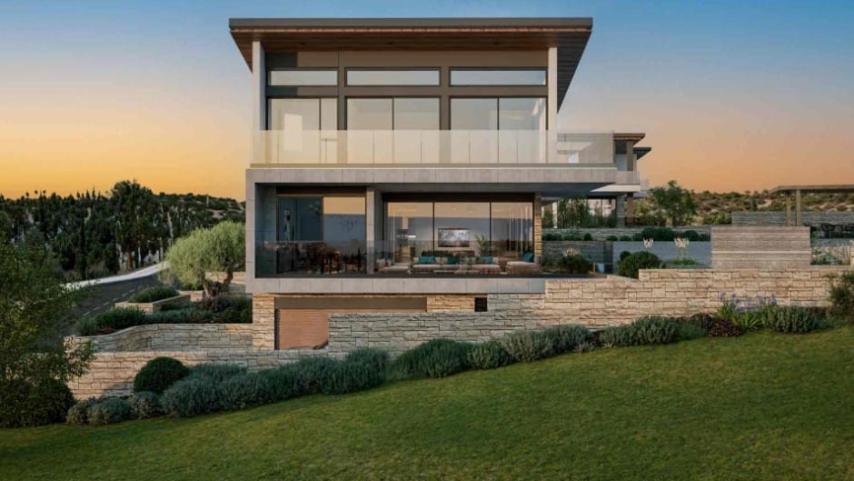 Front elevation of a three-level off-plan villa in Venus Rock, Paphos, with glass balconies, stone walls and landscaped garden