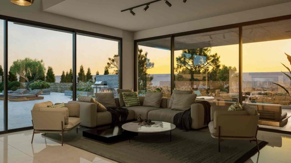 Living room with floor-to-ceiling windows overlooking the outdoor terrace, BBQ area and surrounding landscape at sunset