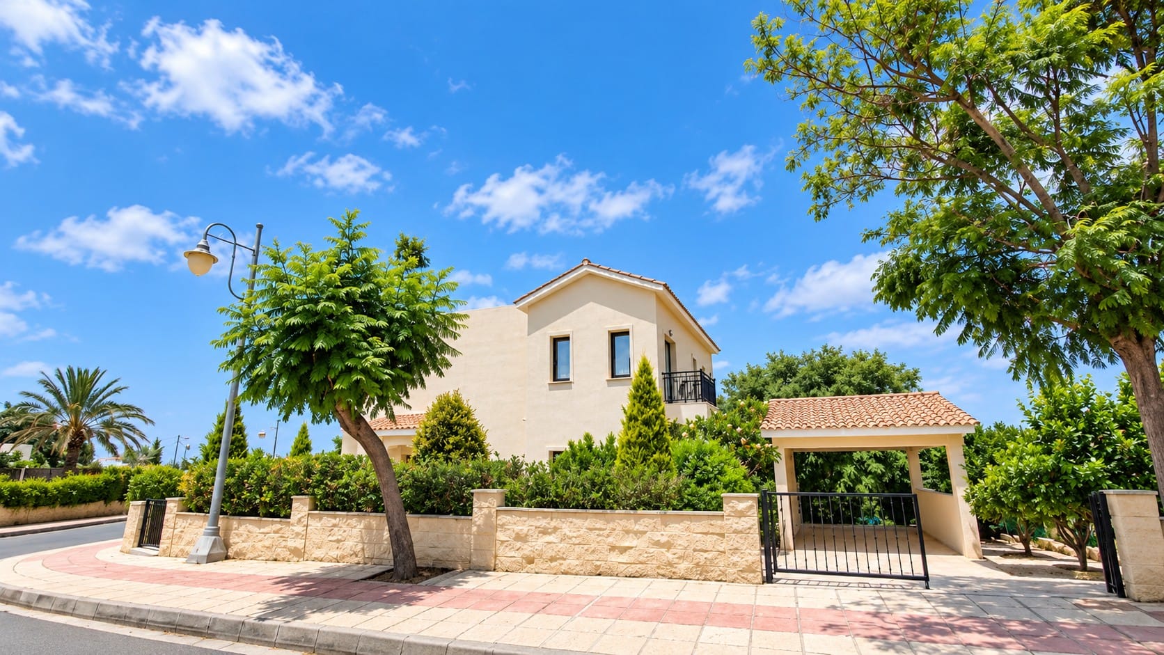 Side view of the villa with balcony, hedged stone boundary wall, gate and covered parking