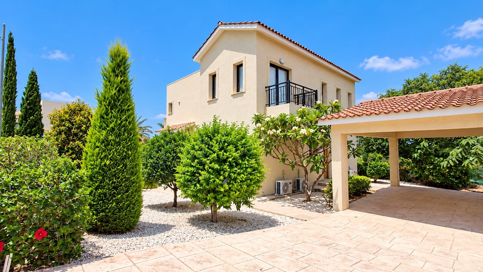 Villa exterior with balcony, landscaped gravel garden, mature trees and covered parking