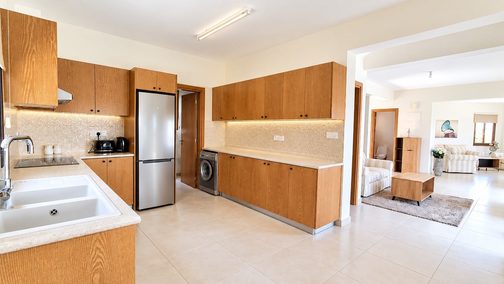 Fitted kitchen with wood-finish cabinets and appliances, opening towards the living area