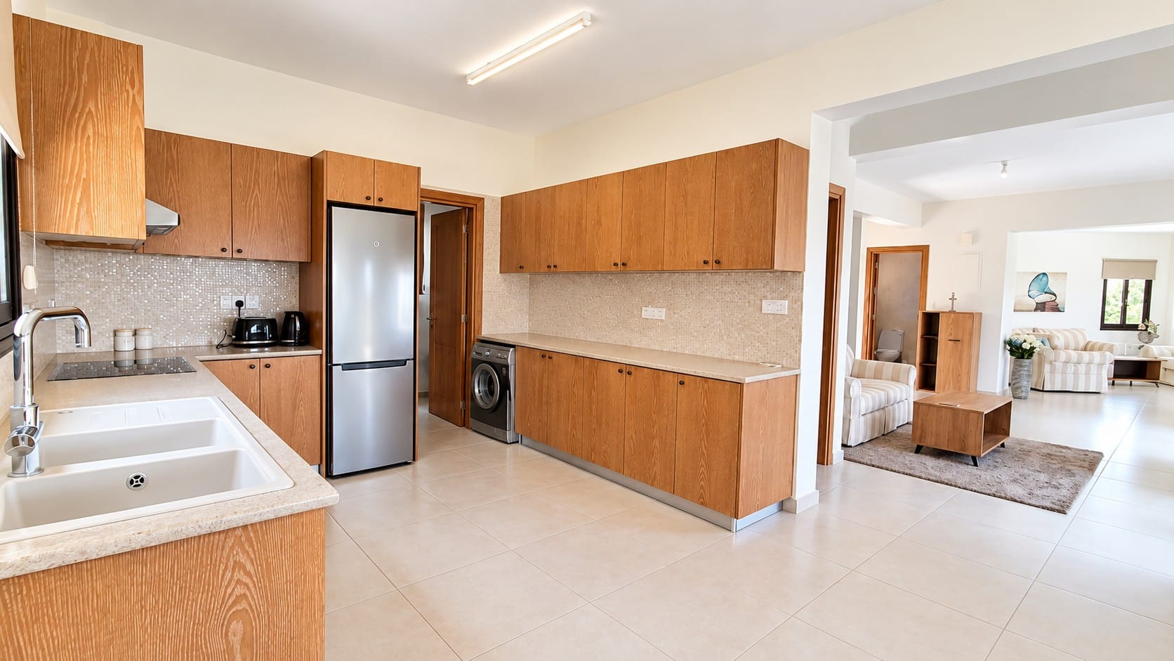 Fitted kitchen with wood-finish cabinets, sink, appliances and view through to the living area