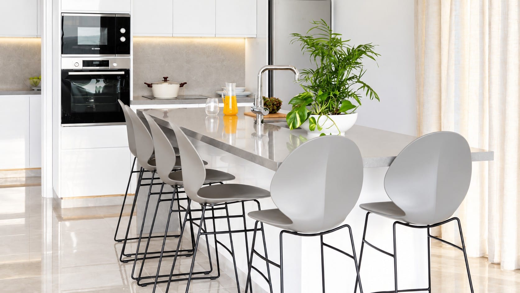 Fitted kitchen with built-in oven and microwave, island with breakfast bar seating and stone-effect worktops