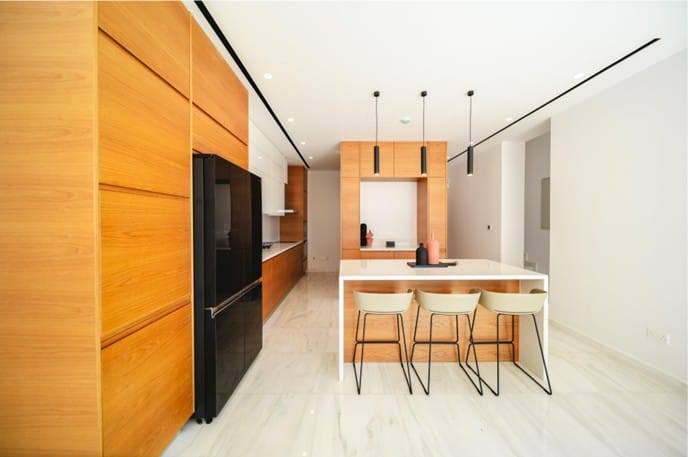 Kitchen with timber-finish cabinetry, island with breakfast bar seating and marble-effect flooring