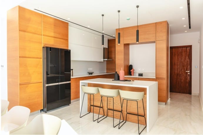 Kitchen with fitted cabinetry, island with bar stools, pendant lighting and marble-effect flooring