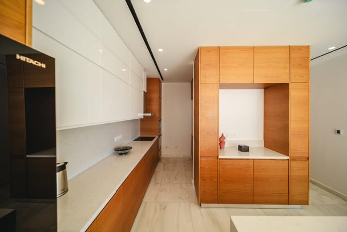 Kitchen with white gloss upper cabinets, timber-finish lower units, long worktop and built-in hob
