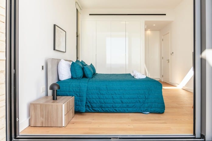 Furnished bedroom with double bed, fitted wardrobes and oak parquet flooring
