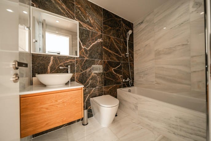 Bathroom with marble-effect wall tiles, vessel washbasin on a timber vanity unit, wall-hung WC and bathtub with shower